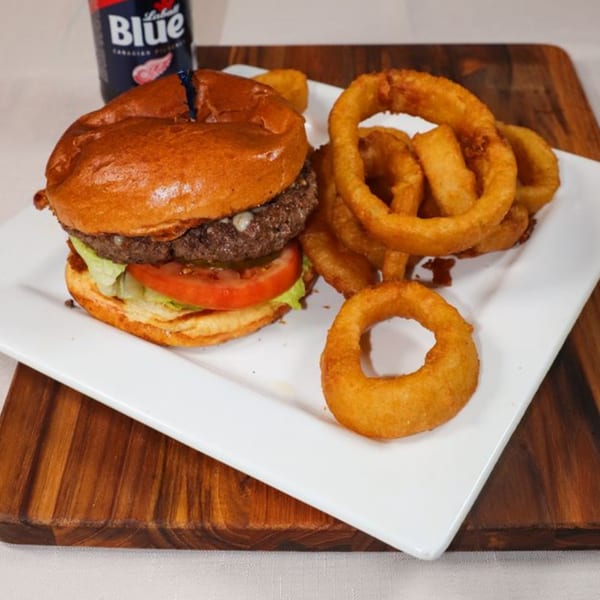 Prime 7 Bar & Restaurant's burger with lettuce, tomato, and onion rings on a white plate.