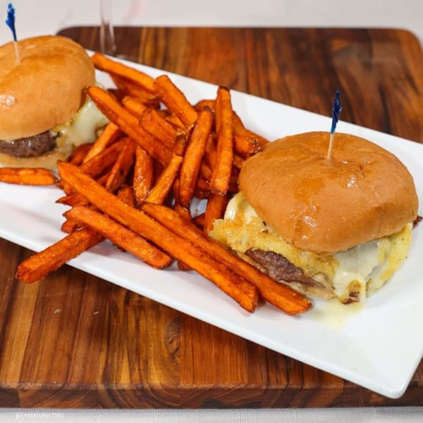 Two cheeseburger sliders with sweet potato fries on a white rectangular plate at Prime 7 Bar & Restaurant.